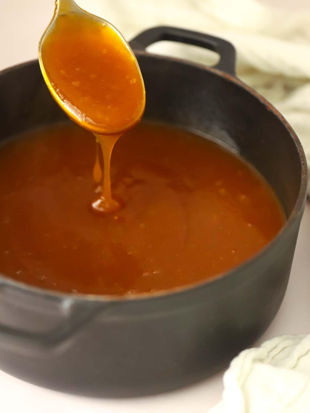 A pan filled with vegetarian gravy, with a spoon dipping in.