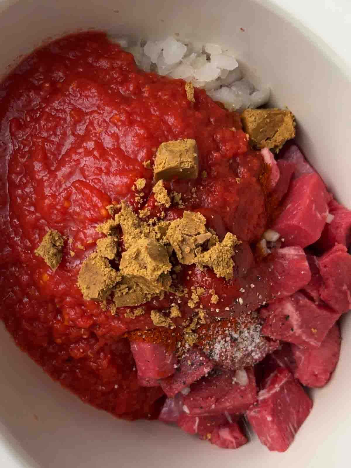 Raw ingredients for slow cooker beef goulash in a slow cooker, ready to cook. Step 1.