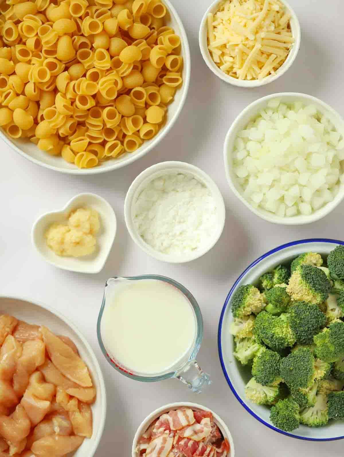 Ingredients for chicken and bacon pasta bake laid out on a counter top.