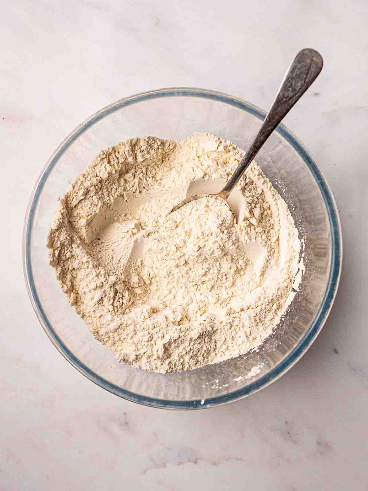 A bowl filled with flour, sugar, baking powder and salt for step 1 in the process for American Pancakes recipe.