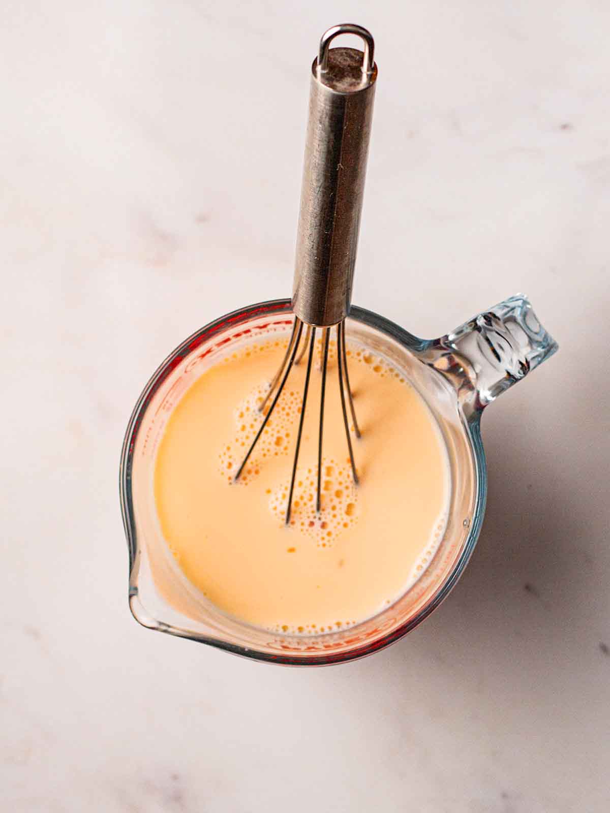 A jug filled with American Pancake mixture, with a whisk sticking out, for step 2 in the recipe.
