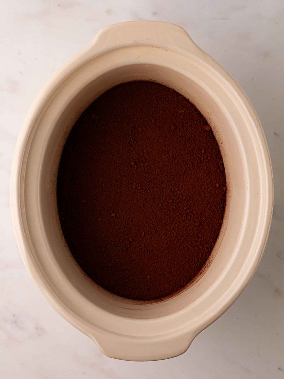 A slow cooker pan with a dry chocolate mixture for step 4 in the recipe for Slow Cooker Mini Egg Easter Pudding.