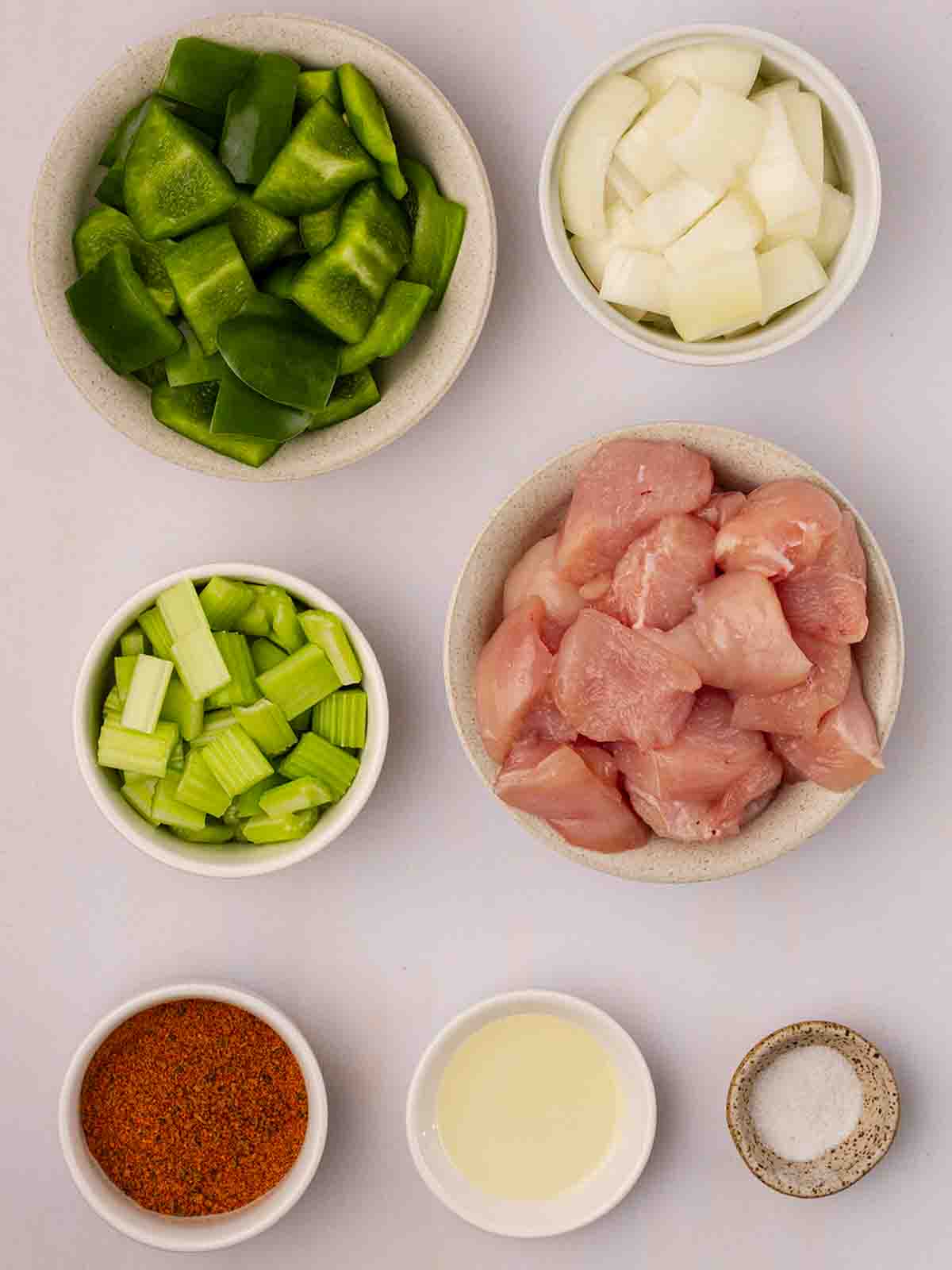 The raw ingredients for Air Fryer Cajun Chicken laid out in bowls on a counter top.