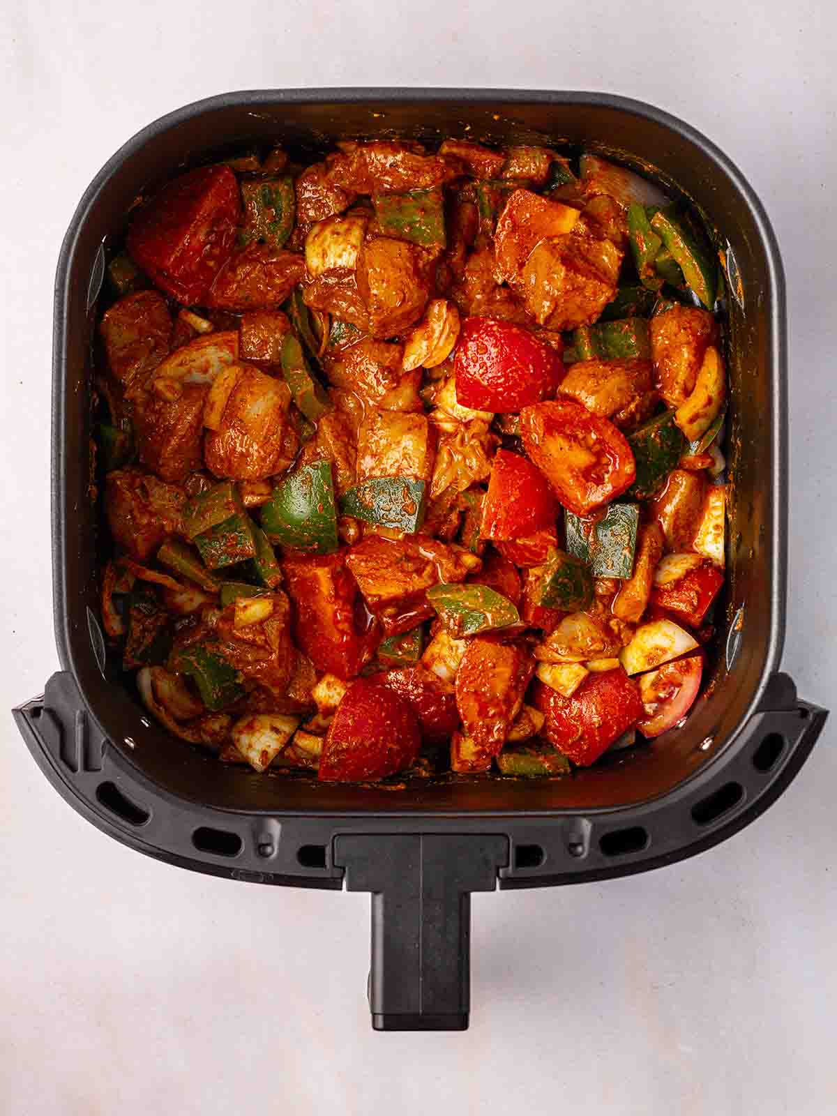 The ingredients for air fryer chicken tikka traybake in an air fryer.