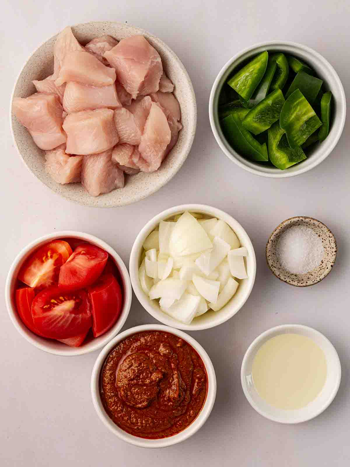 The ingredients for Air Fryer Chicken Tikka Tray Bake laid out in bowls on a counter top.