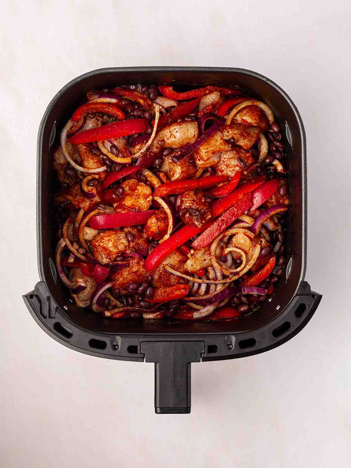 A bird's eye view of an air fryer filled with Air Fryer Mexican Chicken ingredients.