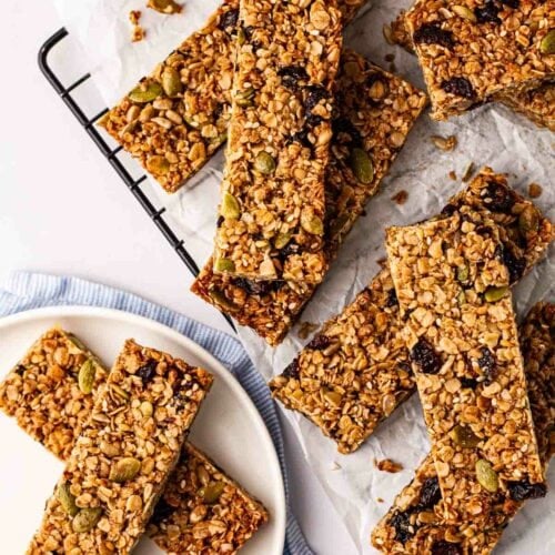 Nutty and fruity granola bars on a wire rack and plate, ready to eat.
