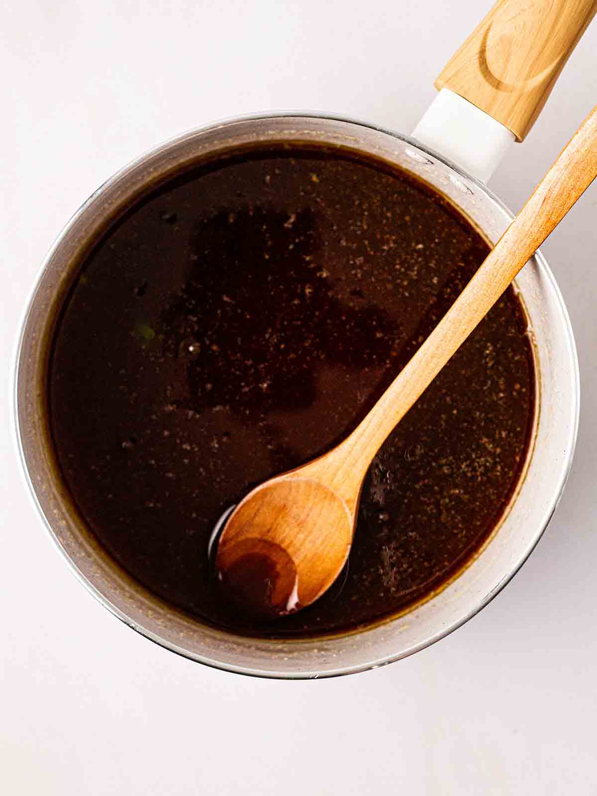 A pan filled with melted butter, honey and sugar with a wooden spoon to mix, for step 1 in the recipe for Granola Bars.