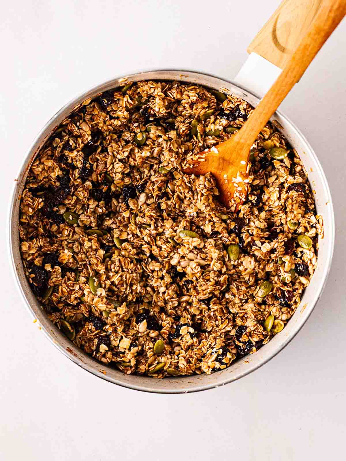 Oats, seeds and dried fruit being mixed in pan for step 2 in the process for making granola bars.