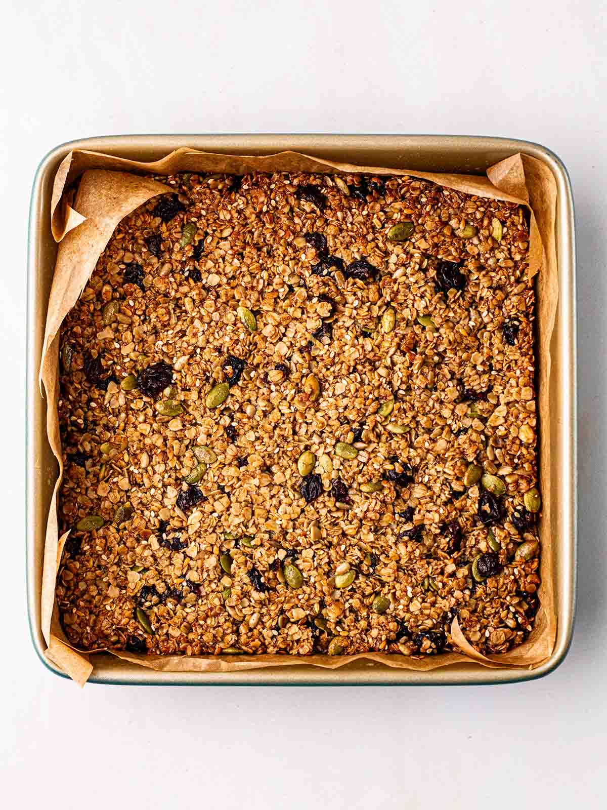 A slab of oats, seeds and fruit, baked in a slab for step 3 in the process for granola bars.