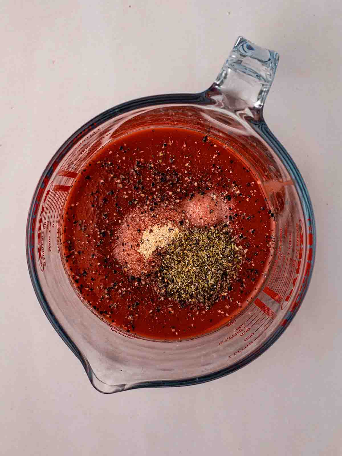A glass jug with a sauce mixture inside, ready to be stirred.