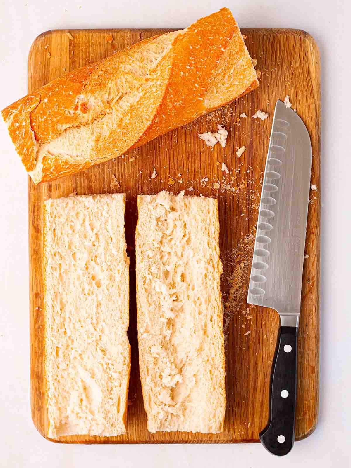 French bread cut in half on a chopping board.