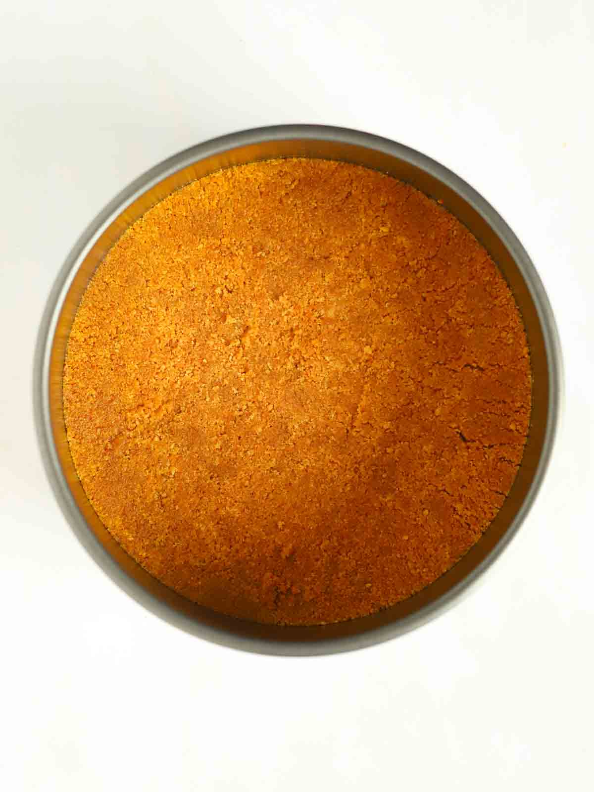 A ginger biscuit base in a tin for step 2 in the process for a Lemon Cheesecake recipe.