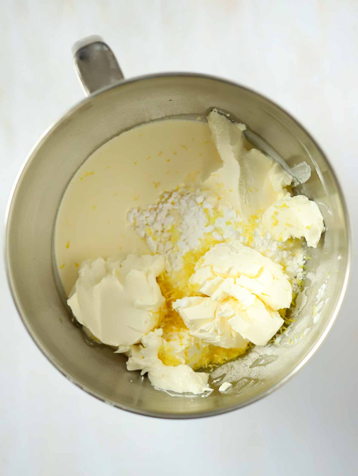 Cream, cream cheese and sugar with lemon zest in a bowl.