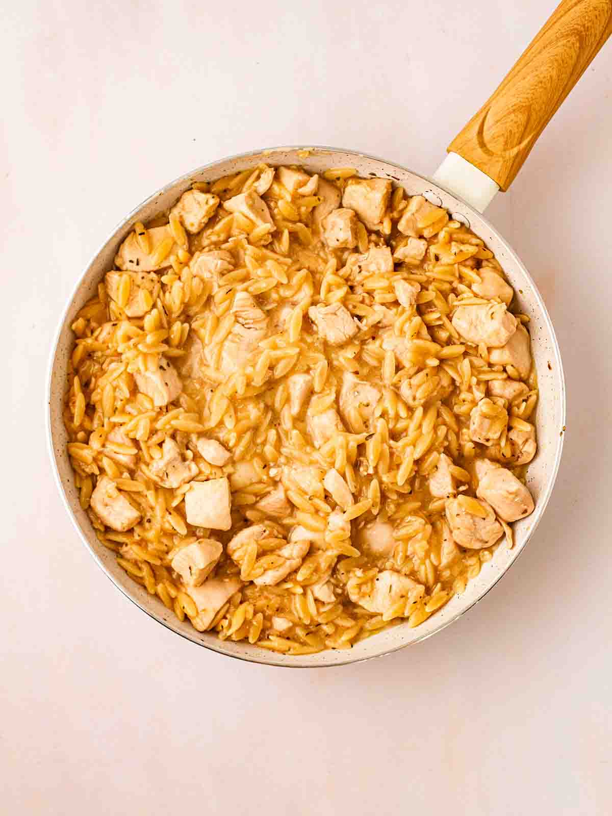 A pan filled with cooked orzo and chicken, ready for the next ingredients in step 3 in the recipe for Lemon Chicken Orzo one pot.
