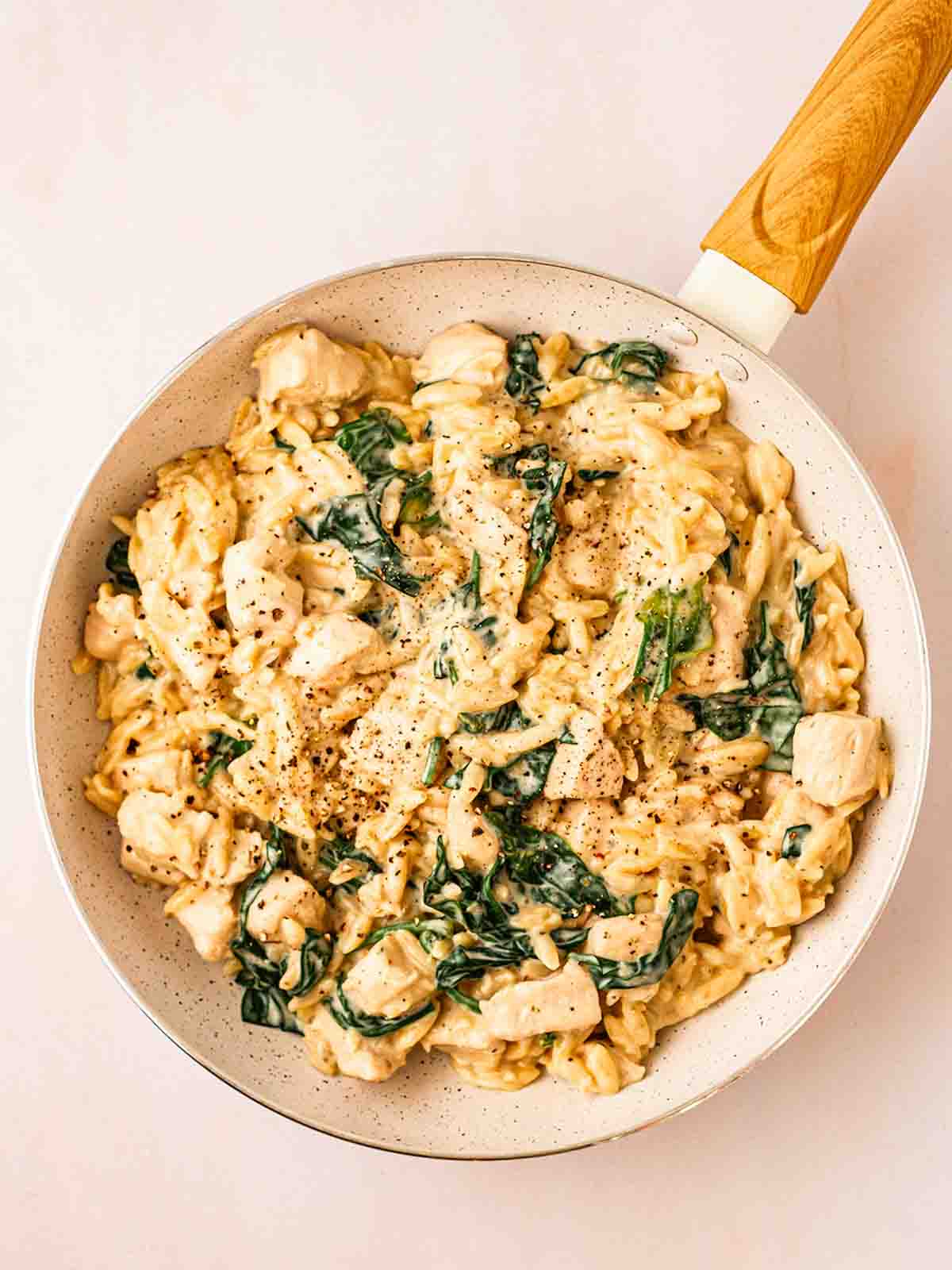 Cooked Lemon Chicken Orzo in a pan with wilted spinach for step 4 in the recipe or Lemon Chicken Orzo.