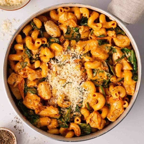 A bird's eye view of past with chicken and a creamy Marry Me sauce, with spinach and parmesan cheese on top.