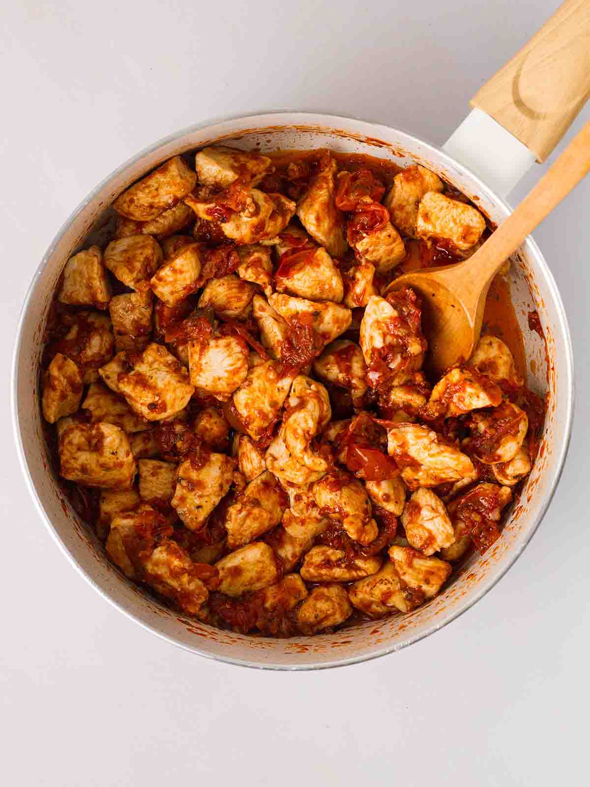 A pan filled with chicken, sun dried tomatoes and spices for step 2 in the recipe for Marry Me Chicken Pasta.