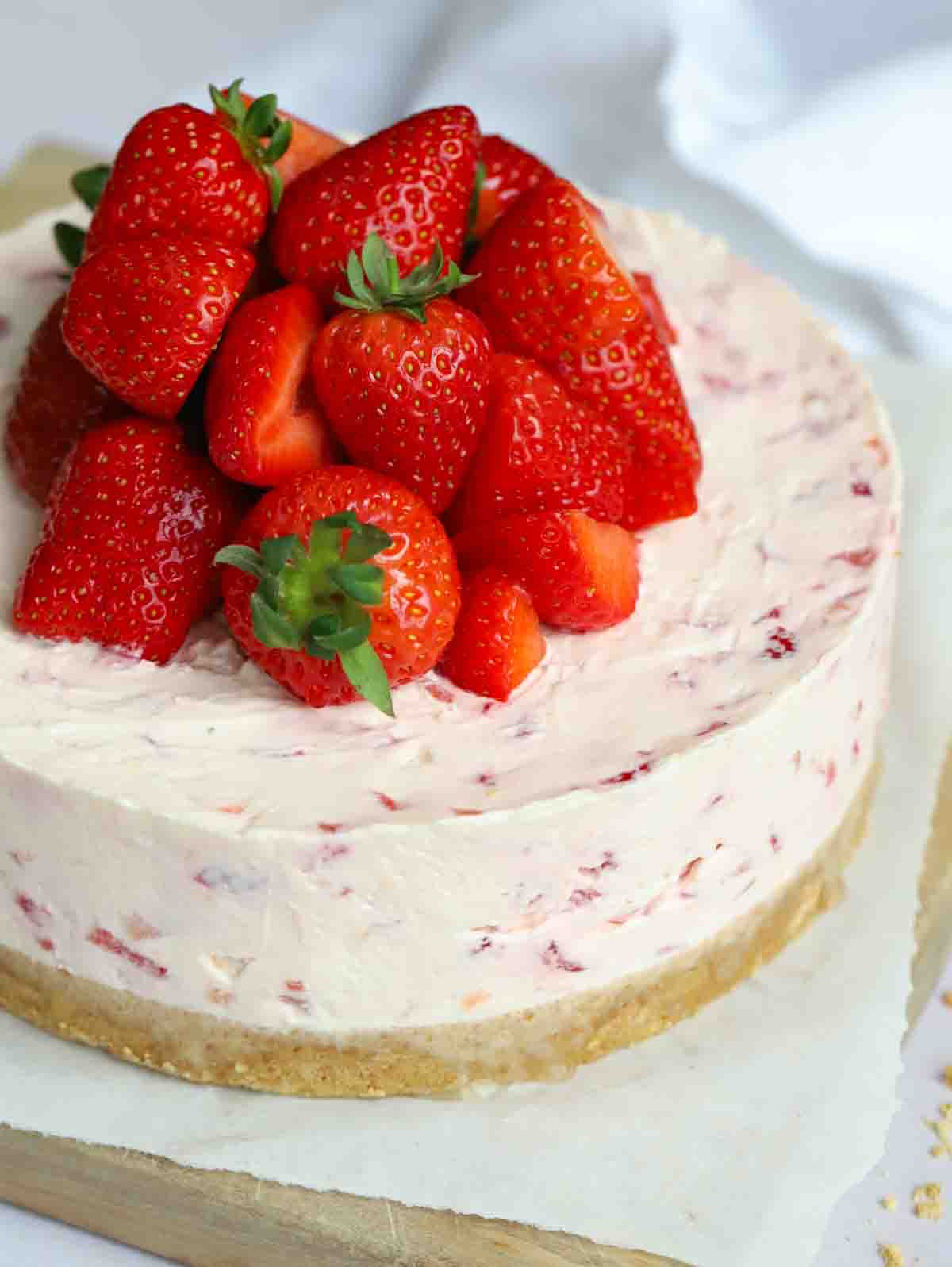 A cheesecake with strawberries piled on top.