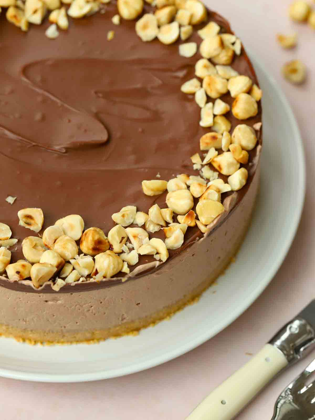 A close up of Nutella Cheesecake on a plate, with the biscuit base, creamy filling and chocolate topping in view.