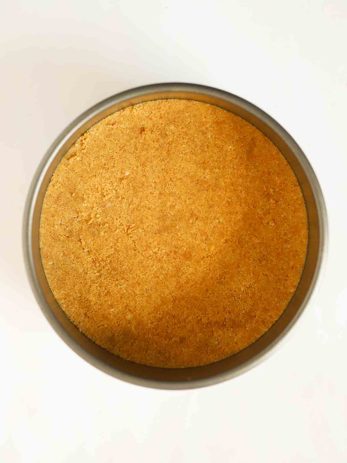 Crushed biscuit pressed into the bottom of a baking tin for step 2 in the recipe for Nutella Cheesecake.