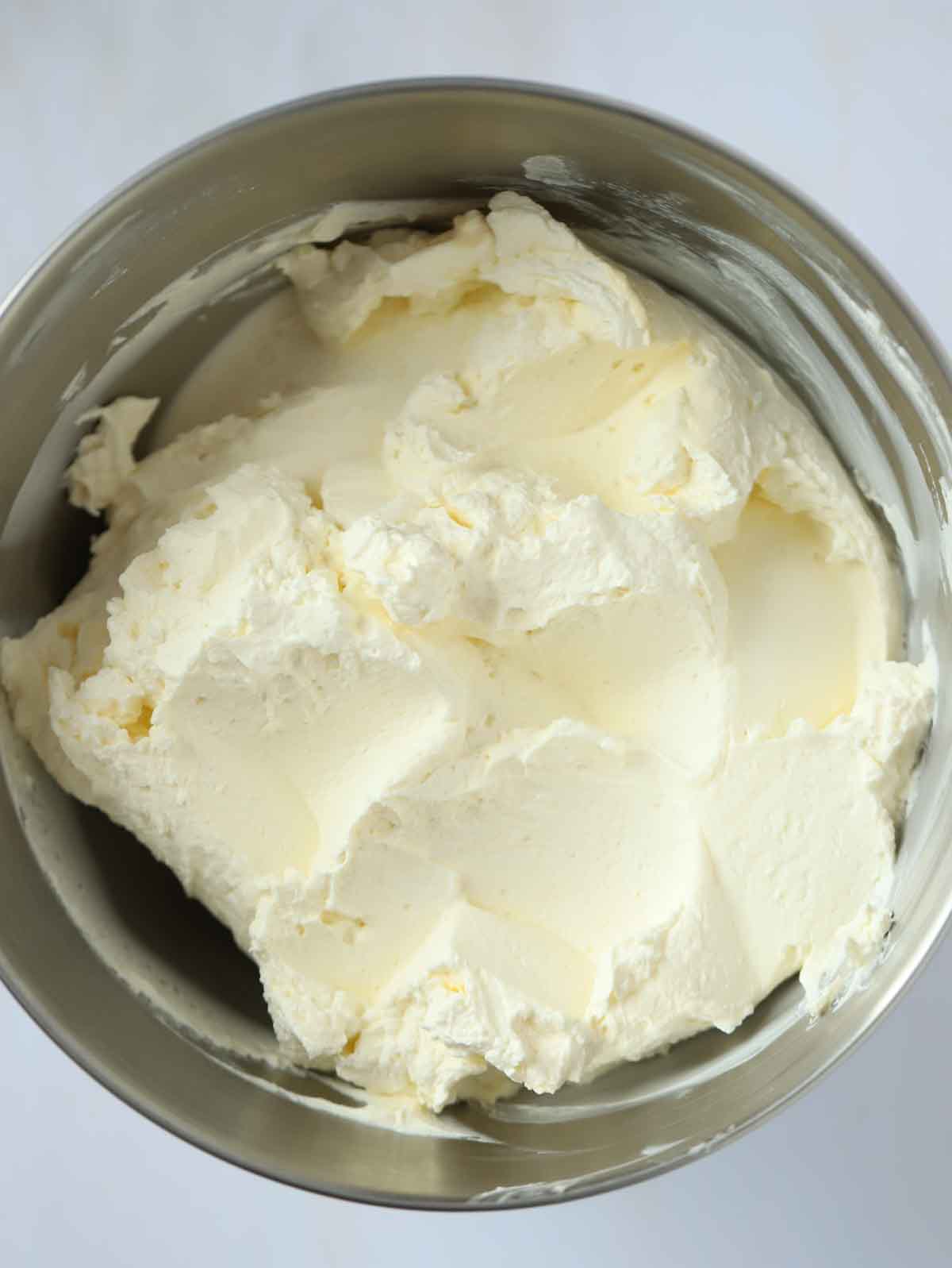 Whipped cream in a bowl for step 3 in the recipe for Vanilla Cheesecake.