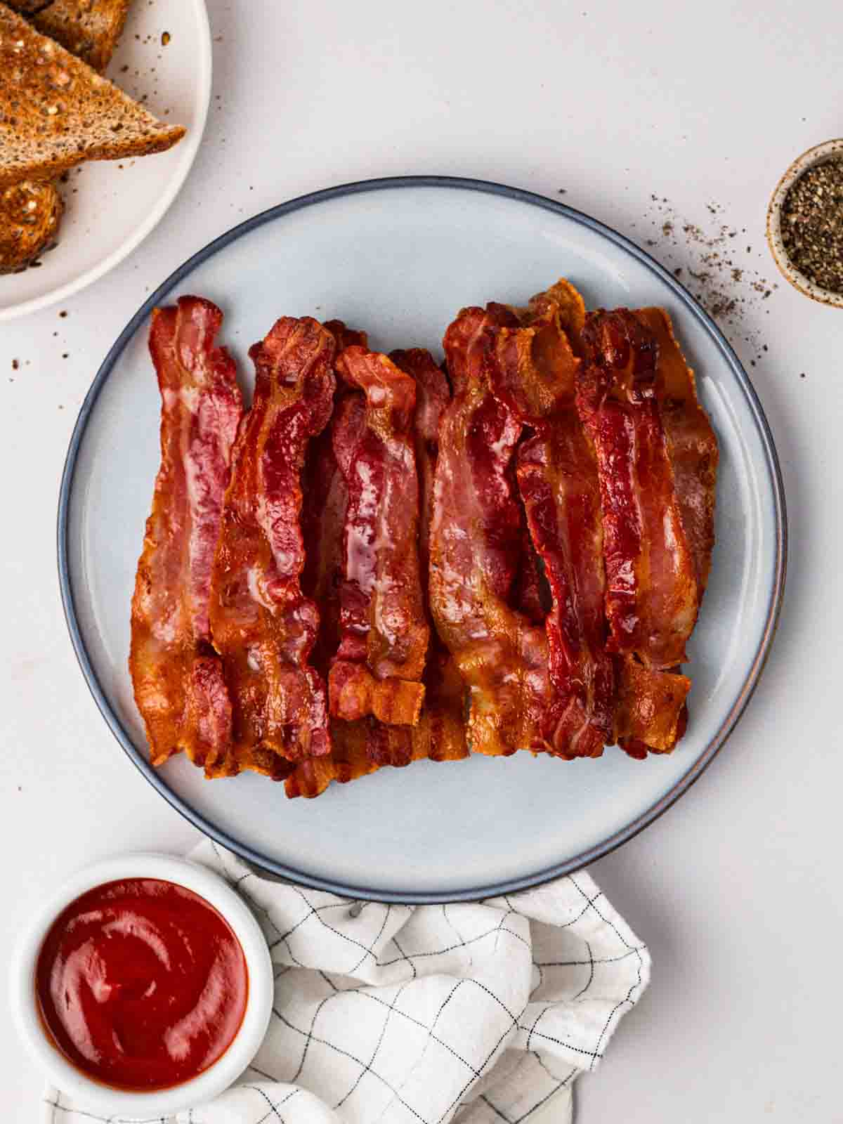 A plate filled with cooked streaky bacon that as been made in the air fryer.