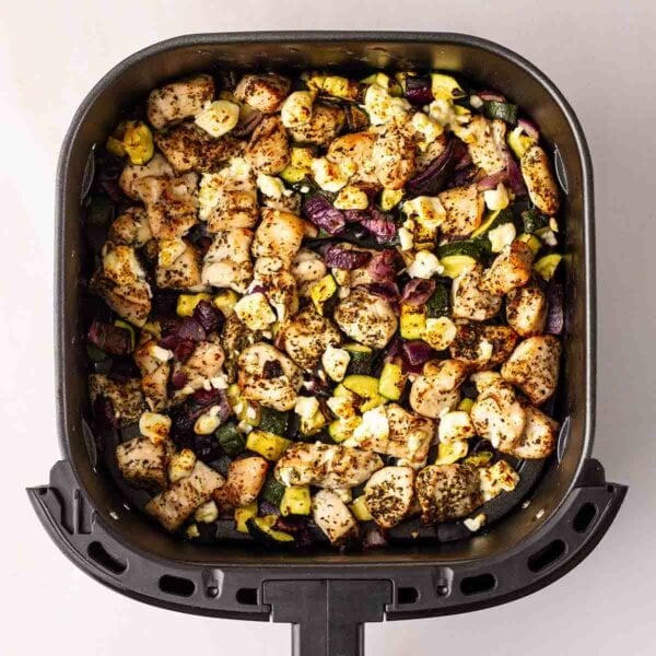 An air fryer with a Greek Chicken Traybake inside.