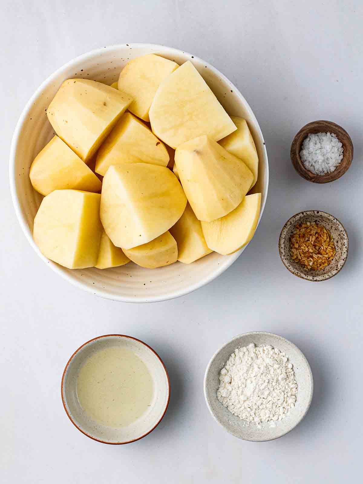 The ingredients for making air fryer roast potatoes laid out on a counter top.