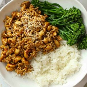 A cashew chicken stir fry made with chicken mince on a plate with rice and broccoli.