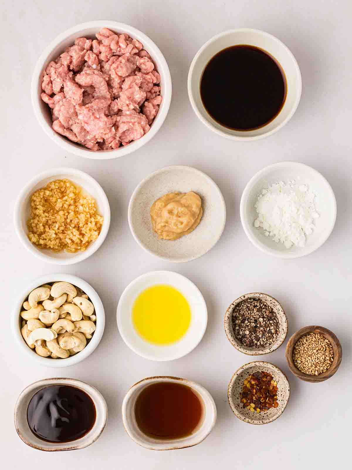 The ingredients for Chicken Cashew Stir Fy laid out in little bowls on a white counter top.