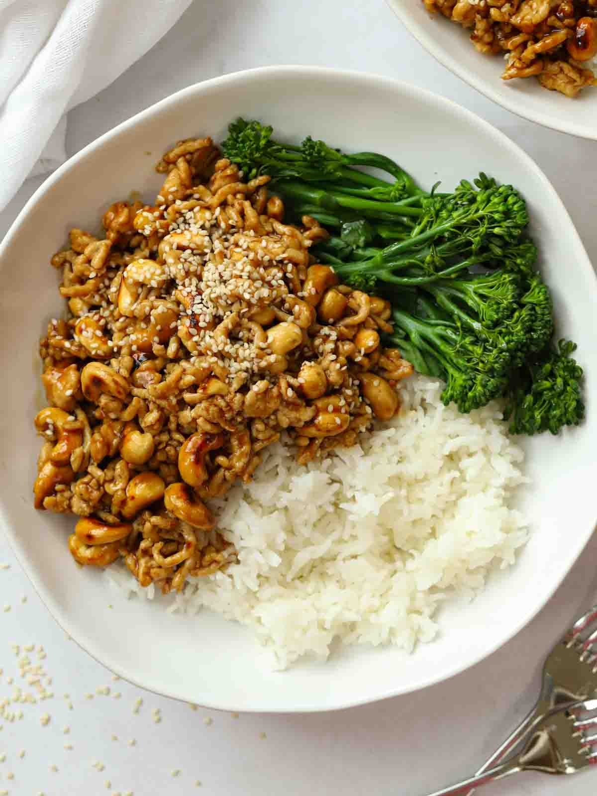 A white bowl with cashew chicken stir fry, white rice and broccoli, ready to eat.