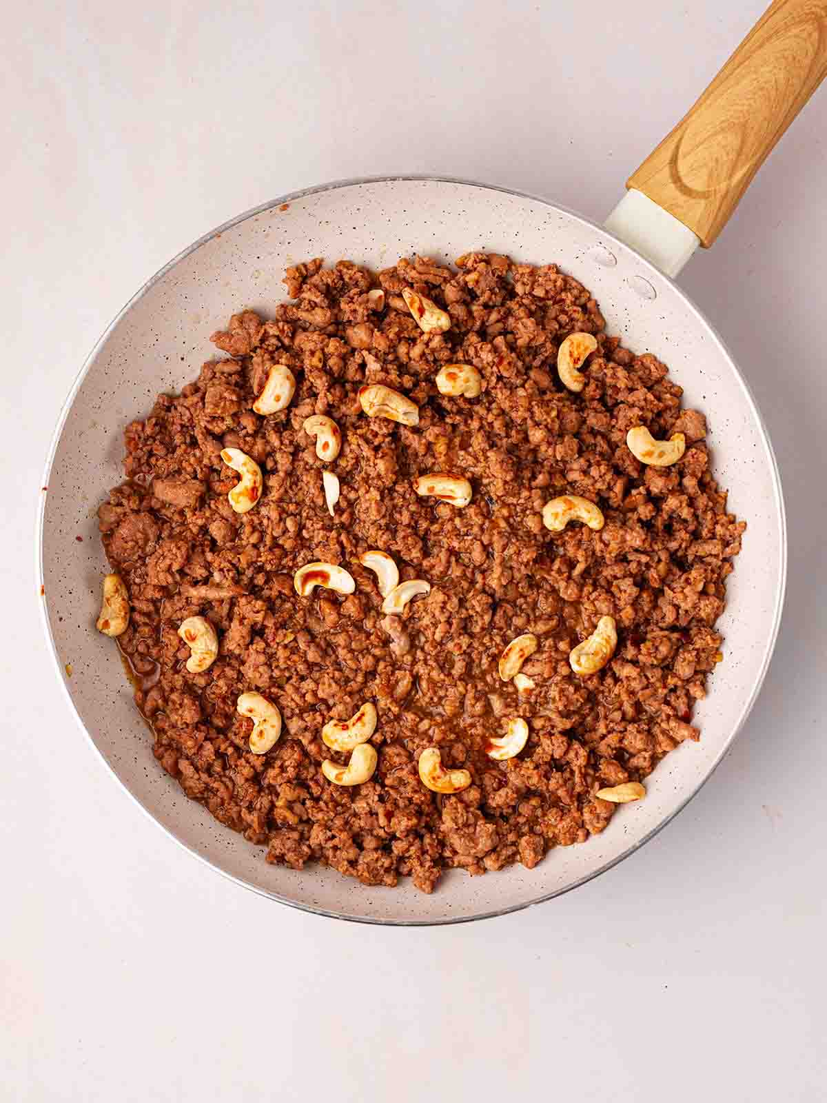 A downwards look at cooked chicken mince with cashews on top for the recipe Cashew Chicken Stir Fry.