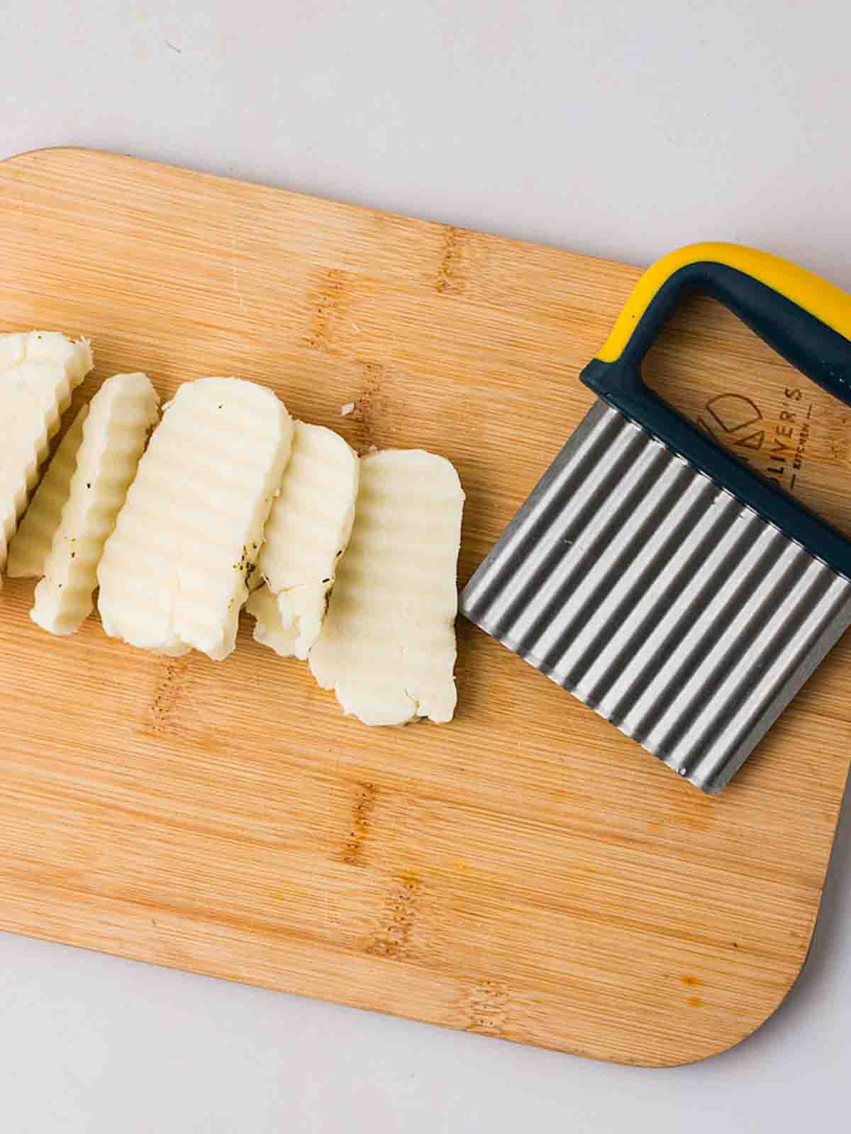A chopping board with a slicer and sliced up halloumi on top for step 2 in the recipe for Halloumi Fajitas.