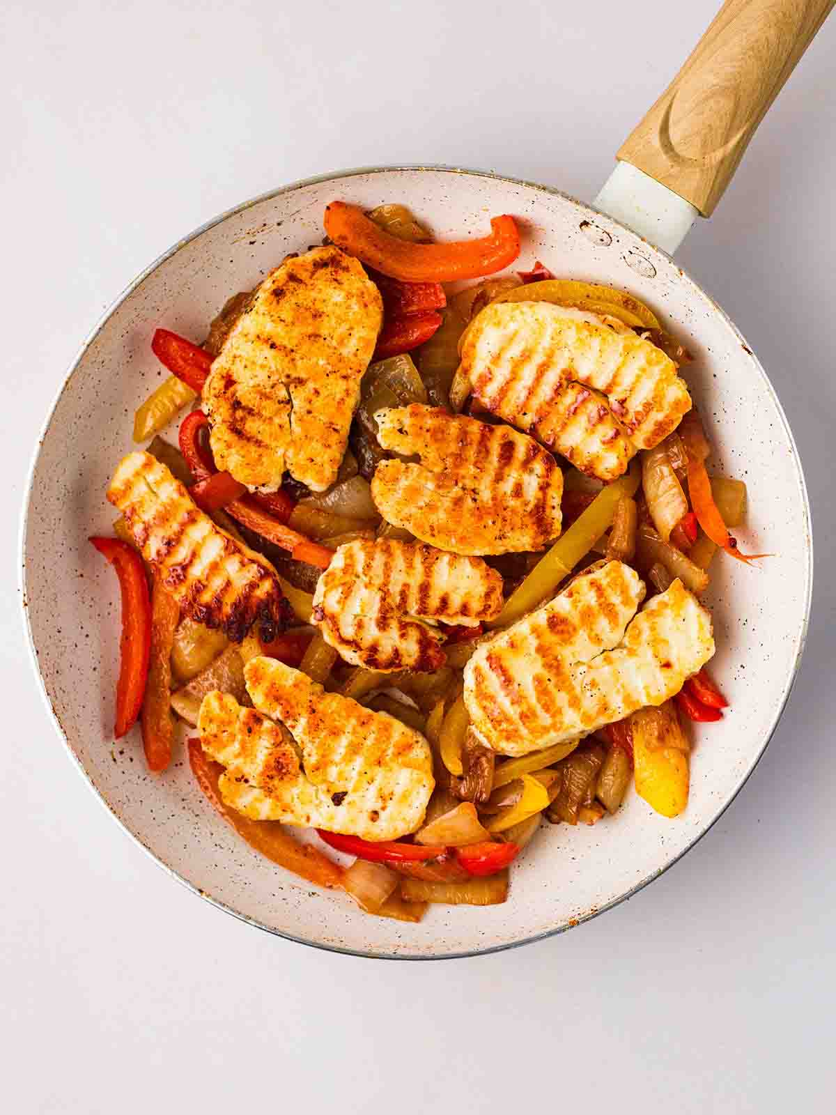 A pan filled with cooked peppers, onion and slices of halloumi.