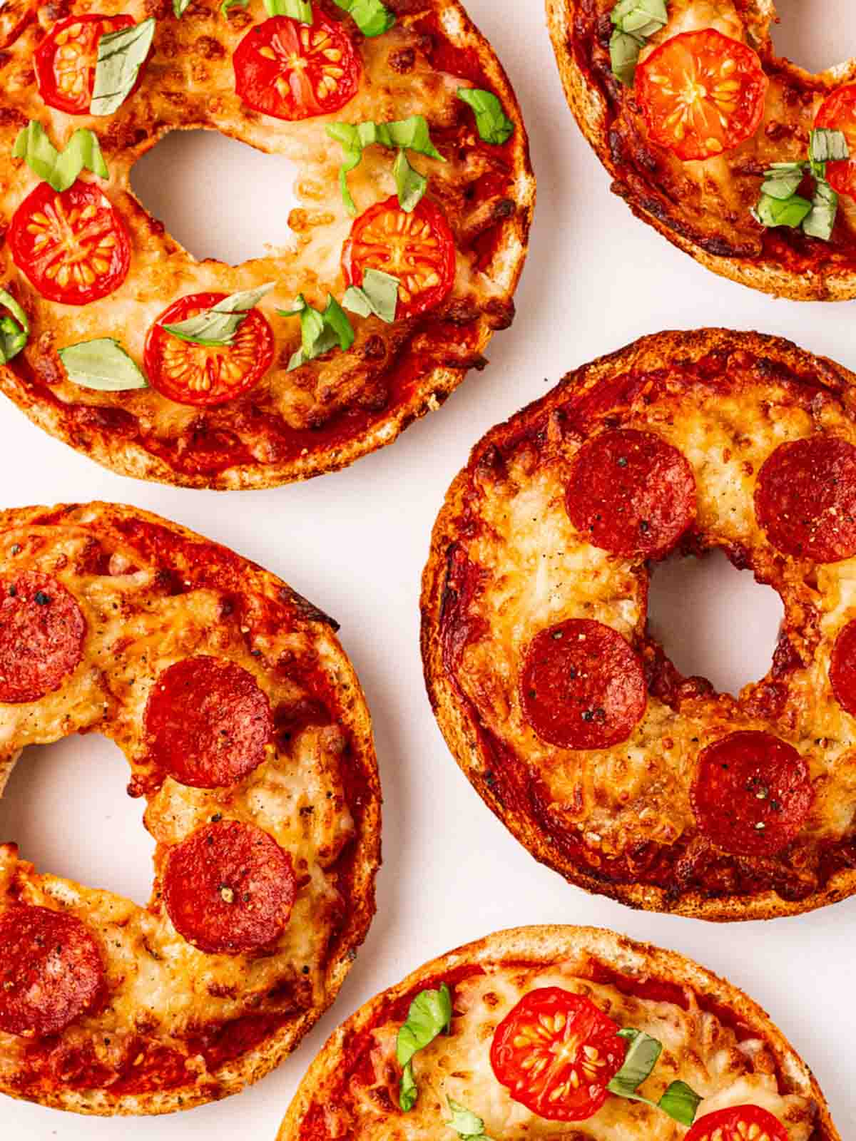 Pizza Bagels on a white counter top with different topping.