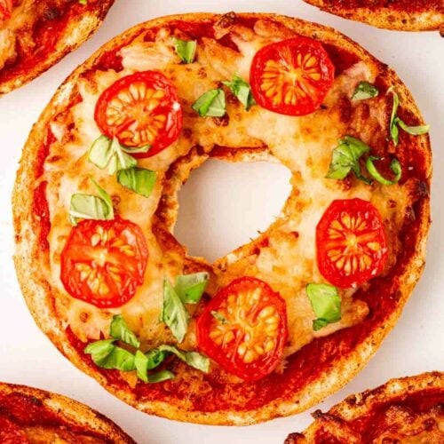 A pizza-style bagel with others round the side.