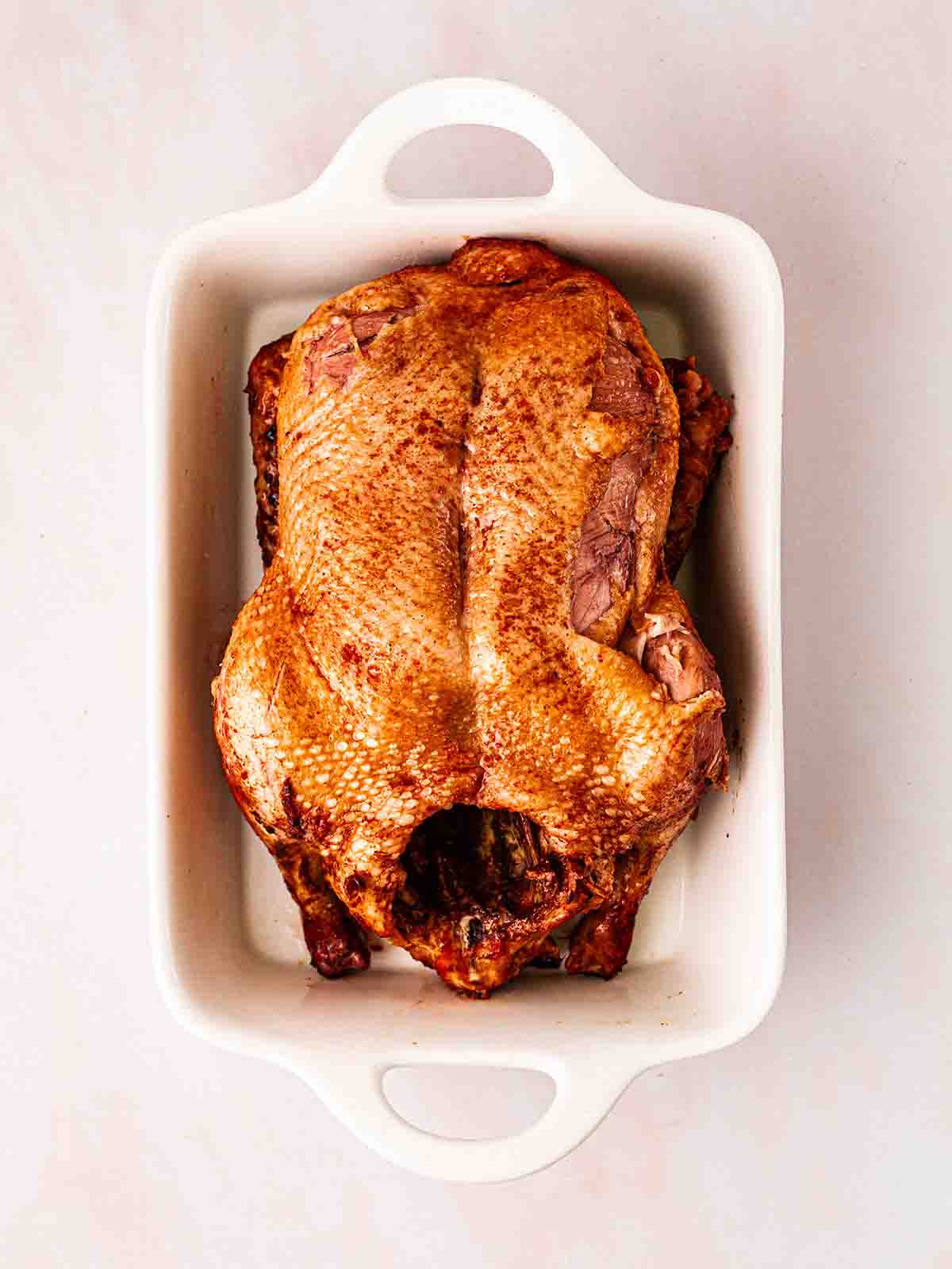 A slow cooked duck in a roasting dish.