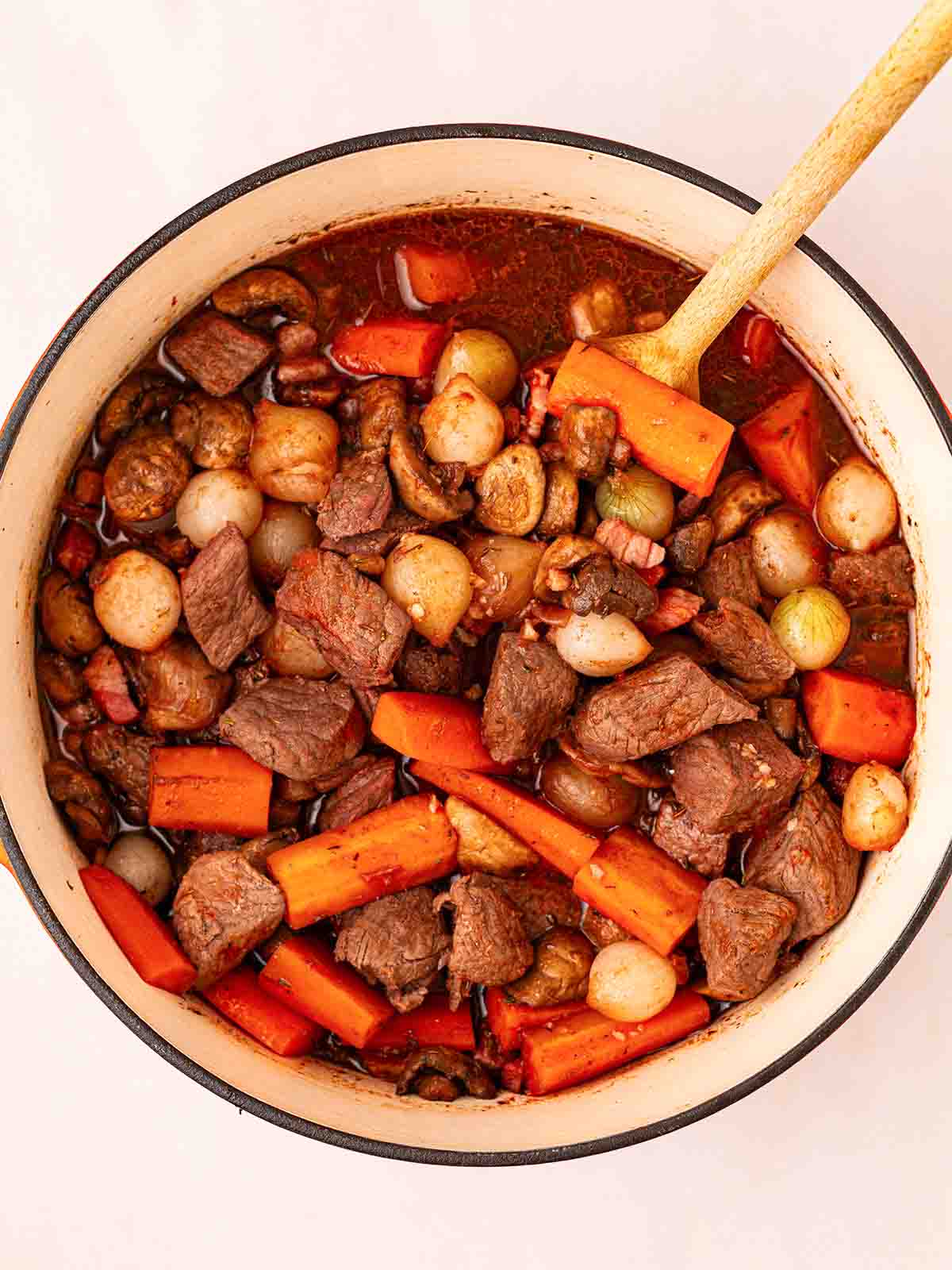 A pan filled with beef bourguignon ingredients, cooking.