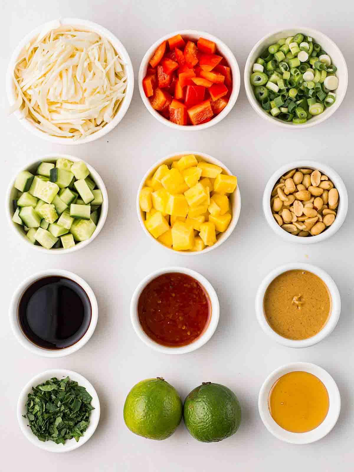 The ingredients for Cabbage Salad laid out in small bowls on a white counter top.