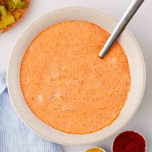 An orange Big Mac sauce in a bowl with spices and ingredients to the side.