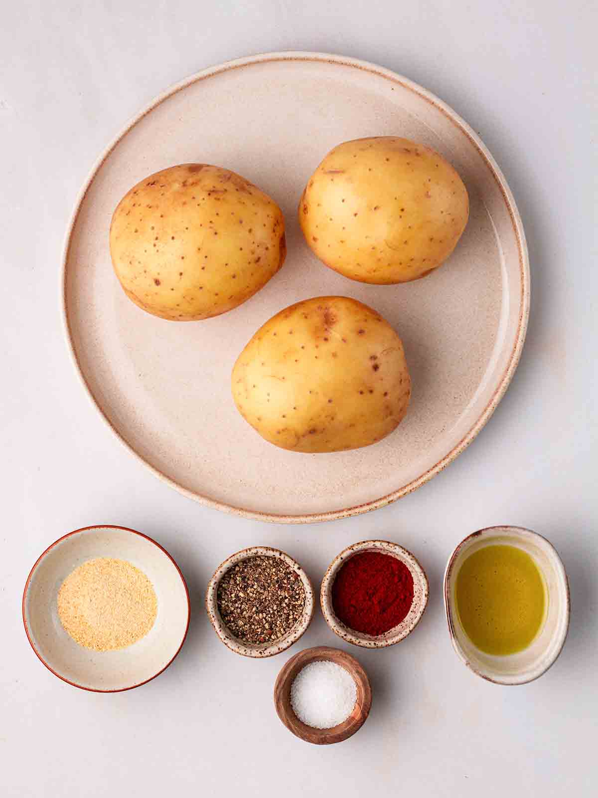 The ingredients for making homemade potato wedges laid out on a white surface.
