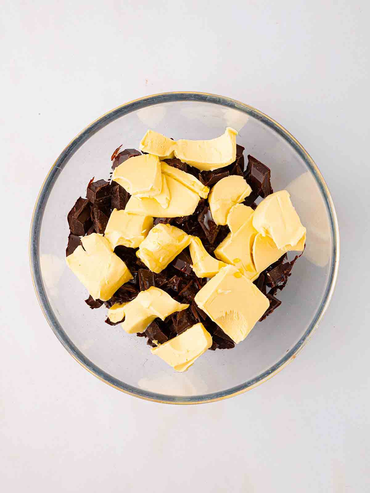Butter and chocolate chunks in a glass bowl for step 1 in the method for Rocky Road recipe.