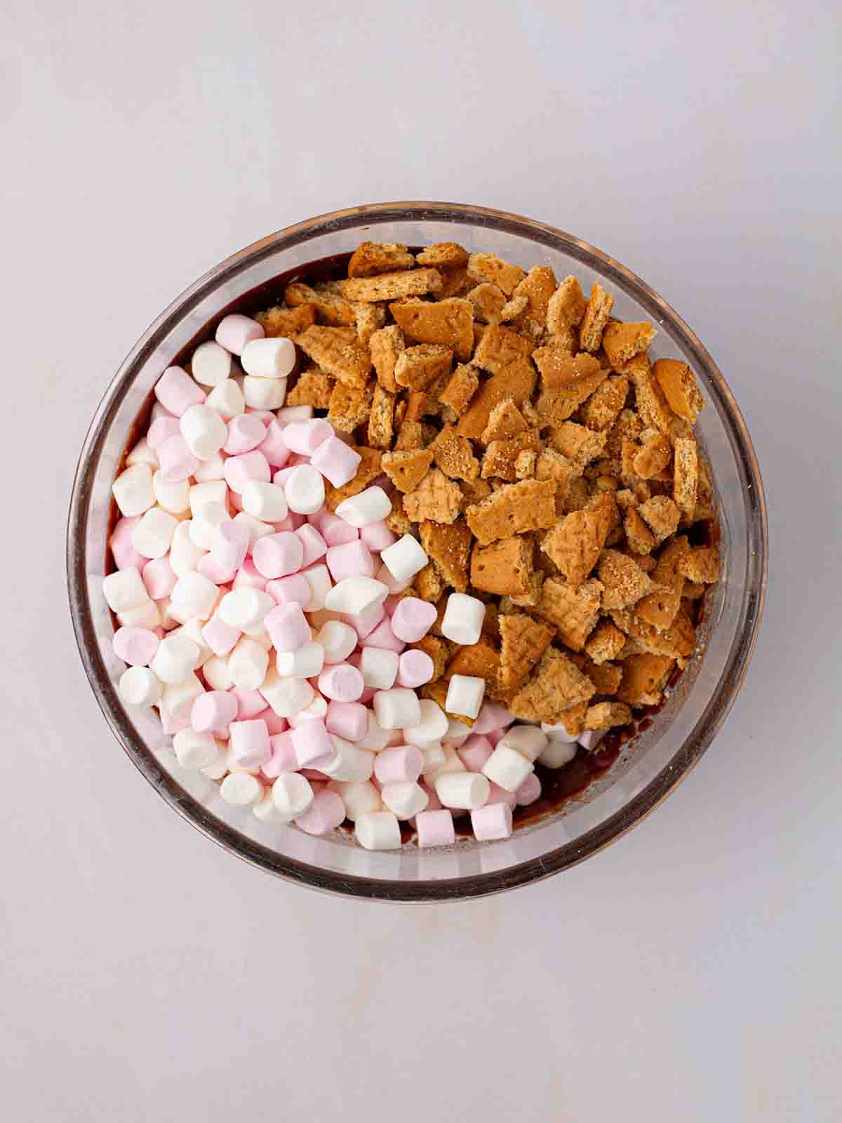 A bowl filled with melted chocolate, marshmallows and digestive biscuits for a Rocky Road recipe.