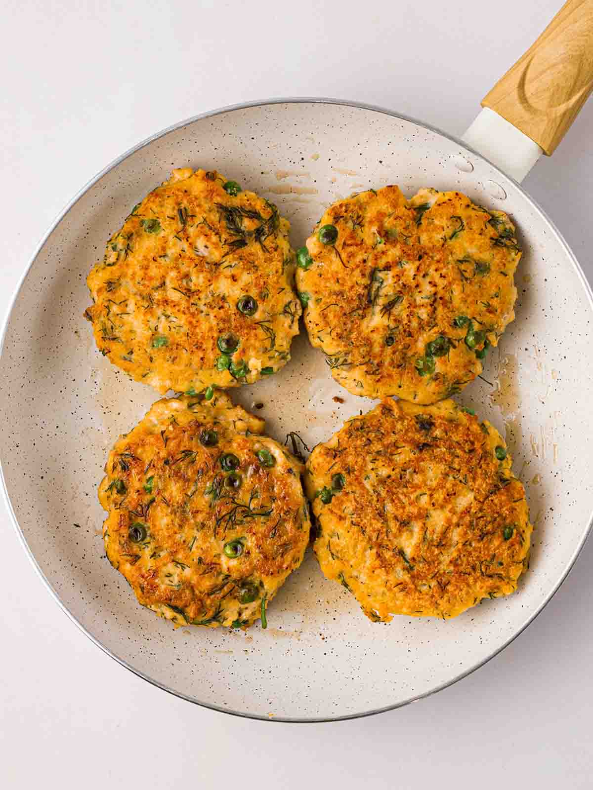Salmon Burgers cooking in a pan.