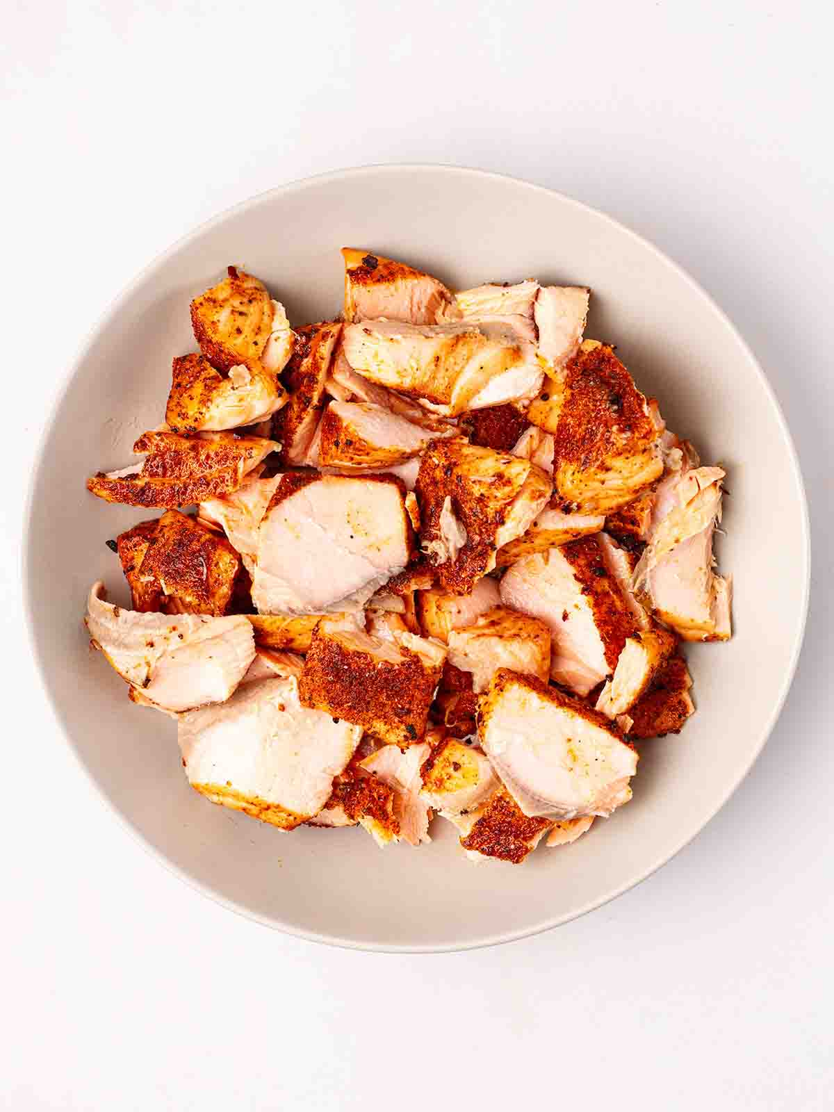 A white bowl filled with chunks of cajun salmon fillets for step 3 in the recipe for Salmon Tacos.