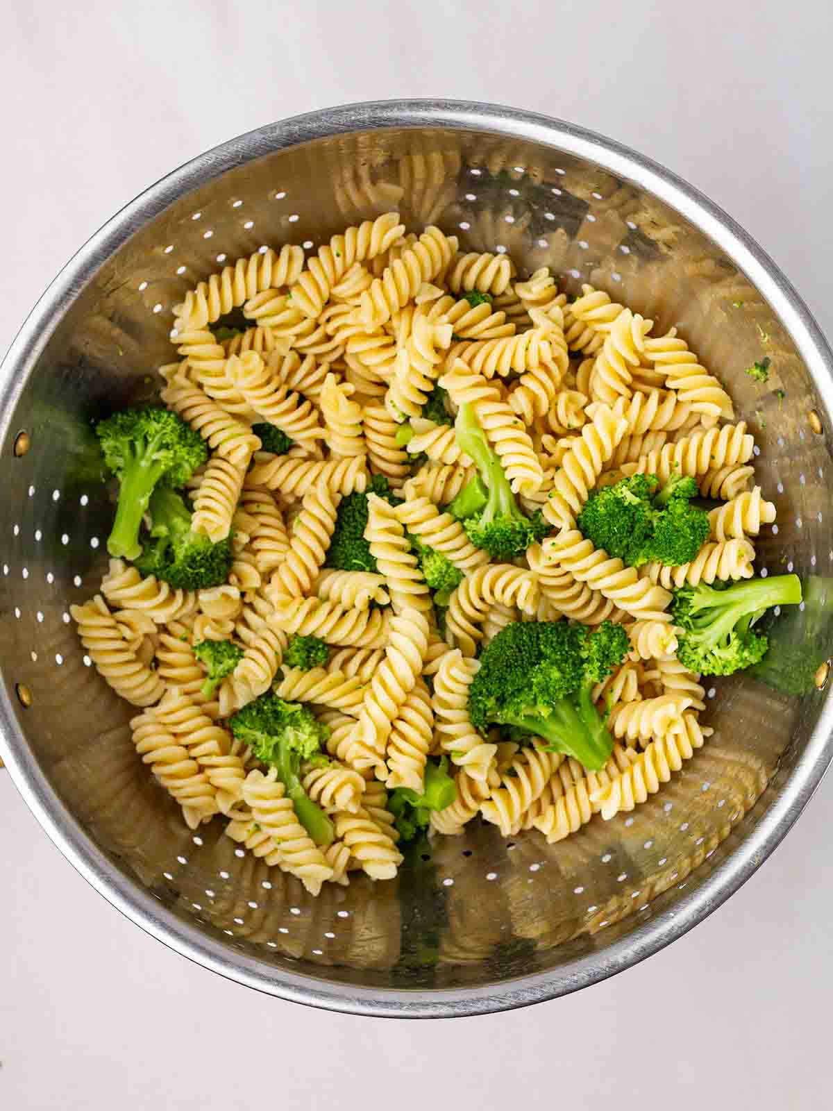 Cooked pasta and broccoli drained in a colander.