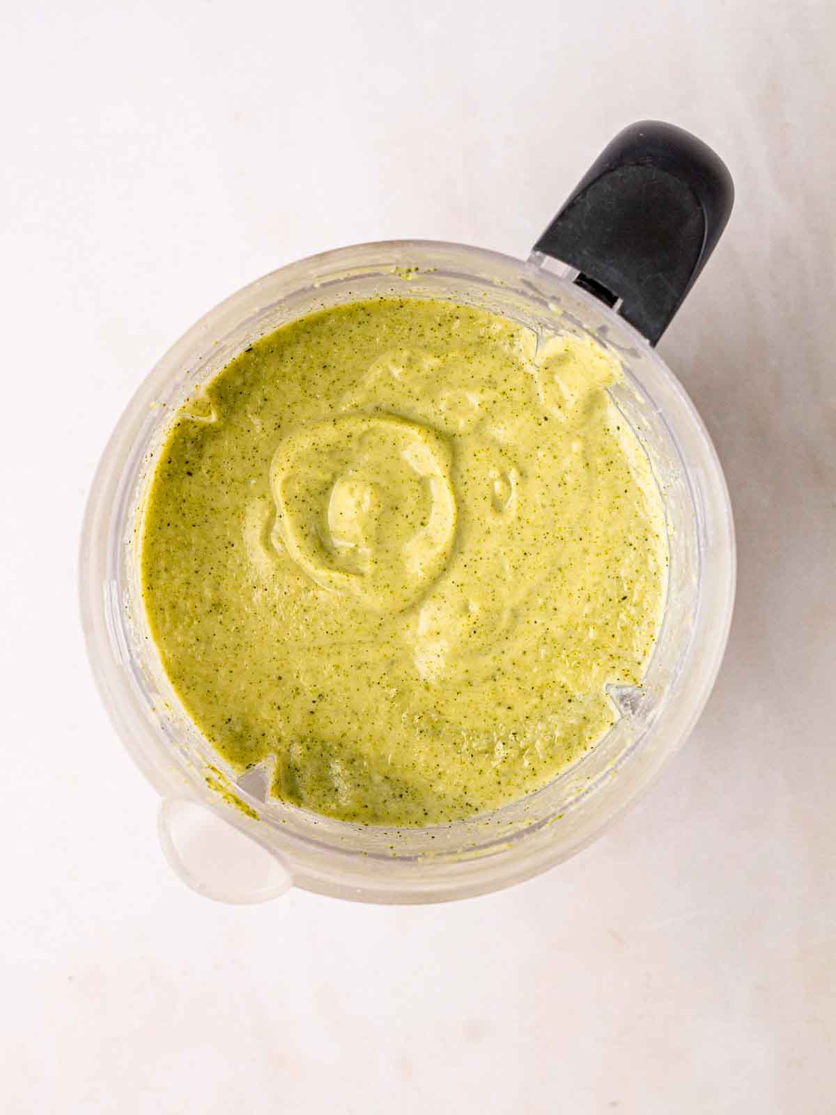 An electric blender with green Broccoli and Stilton Soup inside for step 3 in the recipe.