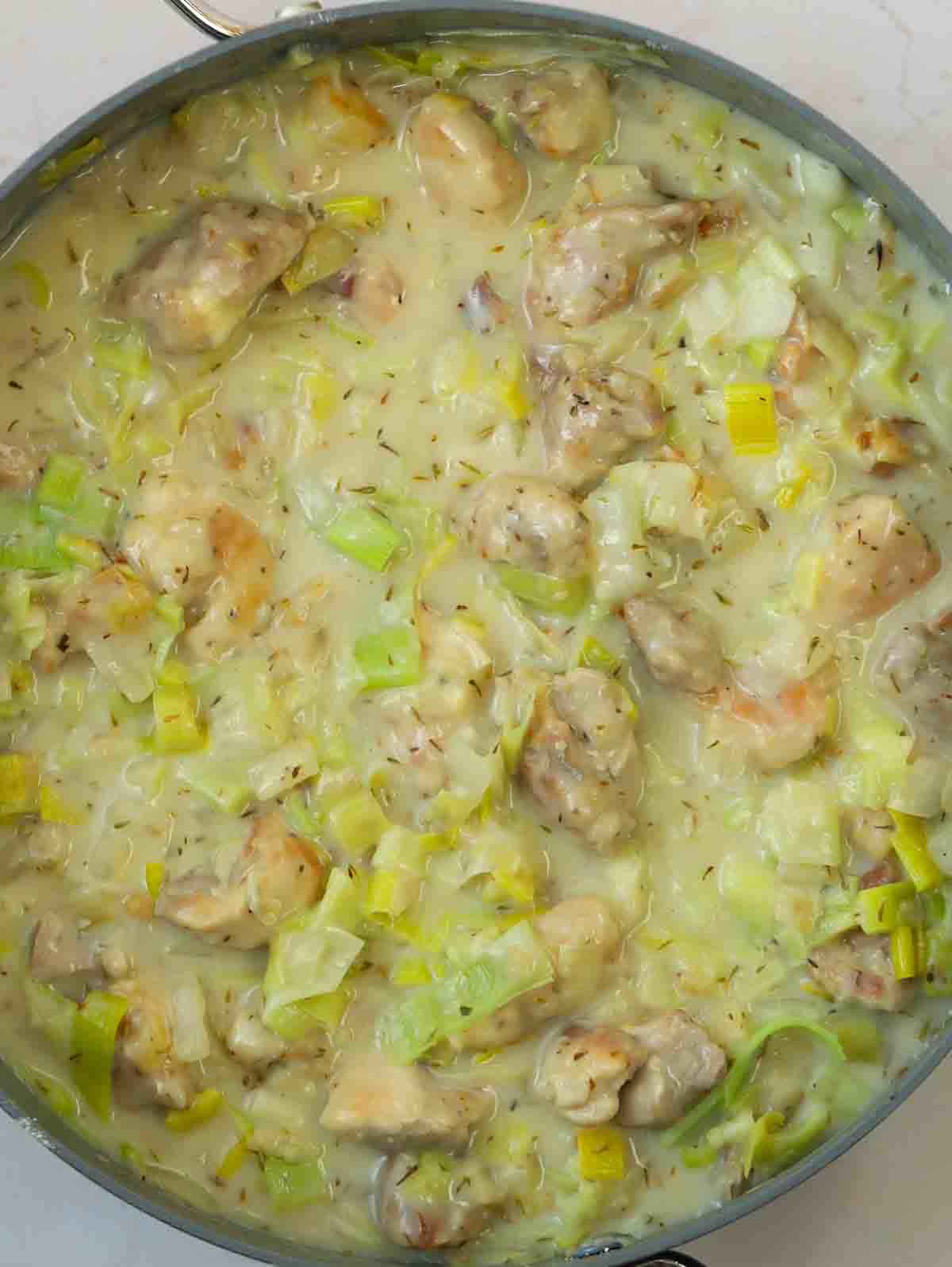 A creamy Chicken and Leek Pie filling cooking in a pan for step 4 in the recipe for Chicken and Leek Pie.