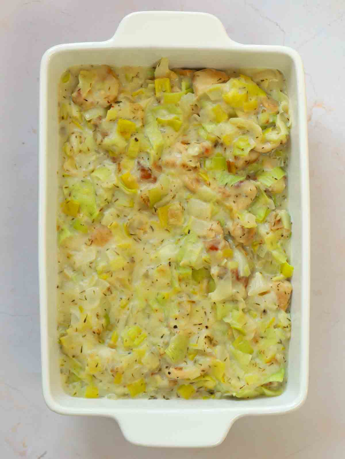 An oven pie dish with pie filling inside for for step 5 in the recipe for Chicken and Leek Pie.